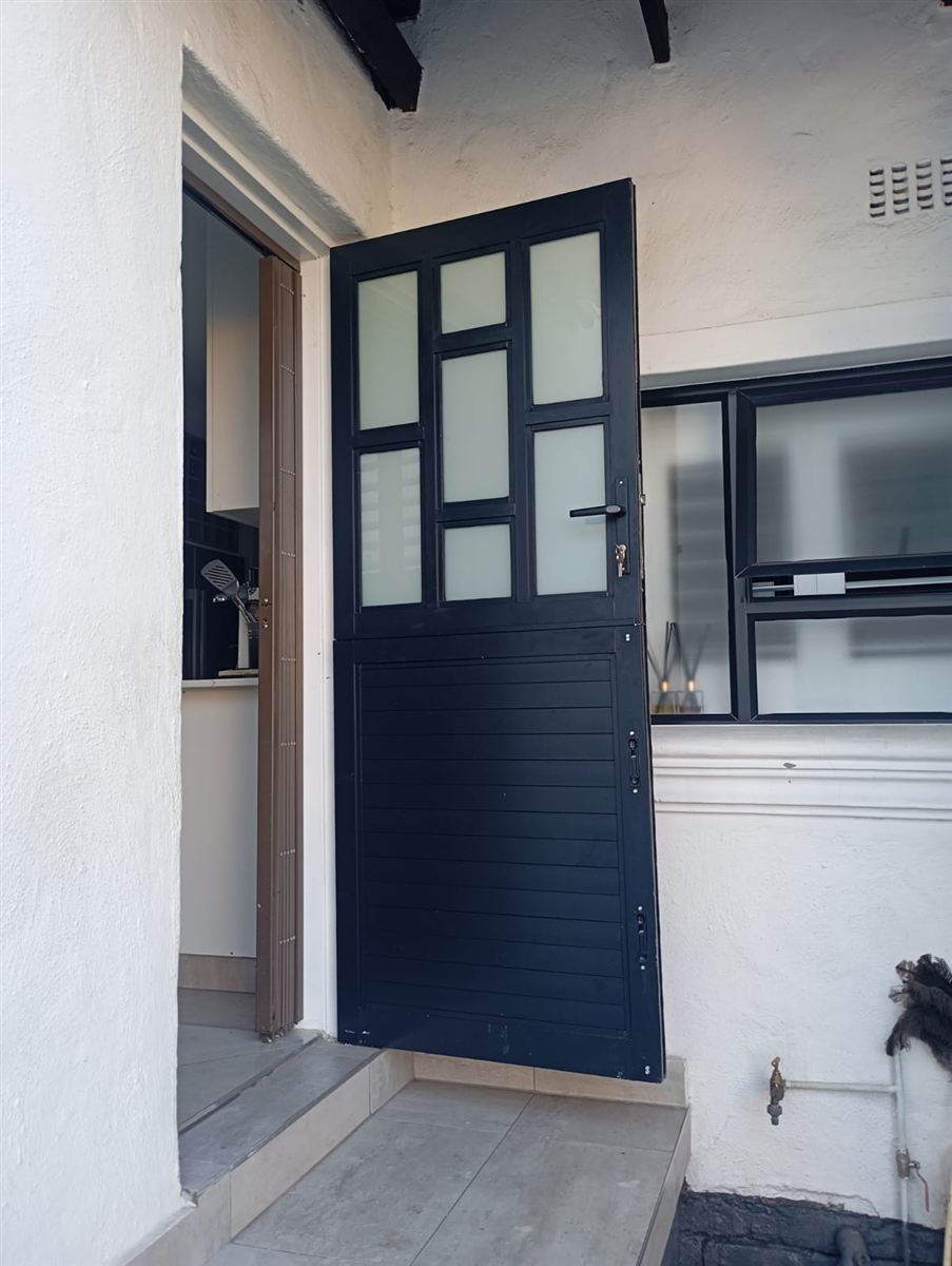 Black framed aluminium entrance door shown partly open